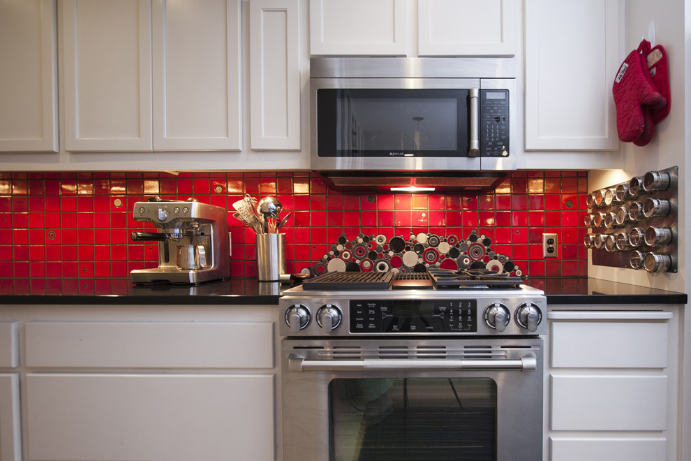 Esempio di una cucina minimalista di medie dimensioni con lavello sottopiano, ante con riquadro incassato, ante bianche, paraspruzzi rosso, paraspruzzi con piastrelle in ceramica, elettrodomestici in acciaio inossidabile, parquet chiaro e penisola