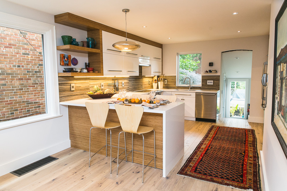 Bild på ett mellanstort funkis kök, med ljust trägolv, brunt stänkskydd, släta luckor, vita skåp, bänkskiva i kvartsit och rostfria vitvaror