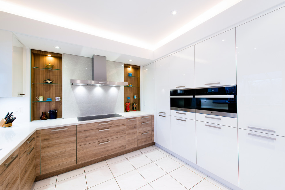 Ejemplo de cocina de tamaño medio con armarios con paneles lisos, salpicadero blanco y electrodomésticos de acero inoxidable