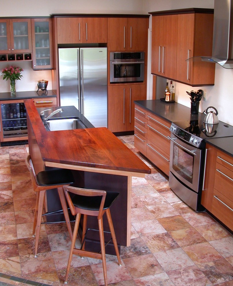Moderne Küche in L-Form mit Küchengeräten aus Edelstahl, Unterbauwaschbecken, hellbraunen Holzschränken, Arbeitsplatte aus Holz, Küchenrückwand in Beige und Glasrückwand in Phoenix