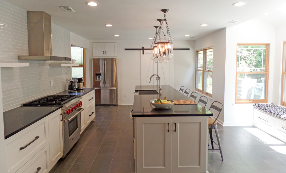 Bild på ett stort funkis kök med öppen planlösning, med en rustik diskho, skåp i shakerstil, vita skåp, bänkskiva i kvarts, grått stänkskydd, stänkskydd i glaskakel, rostfria vitvaror, klinkergolv i keramik och en köksö