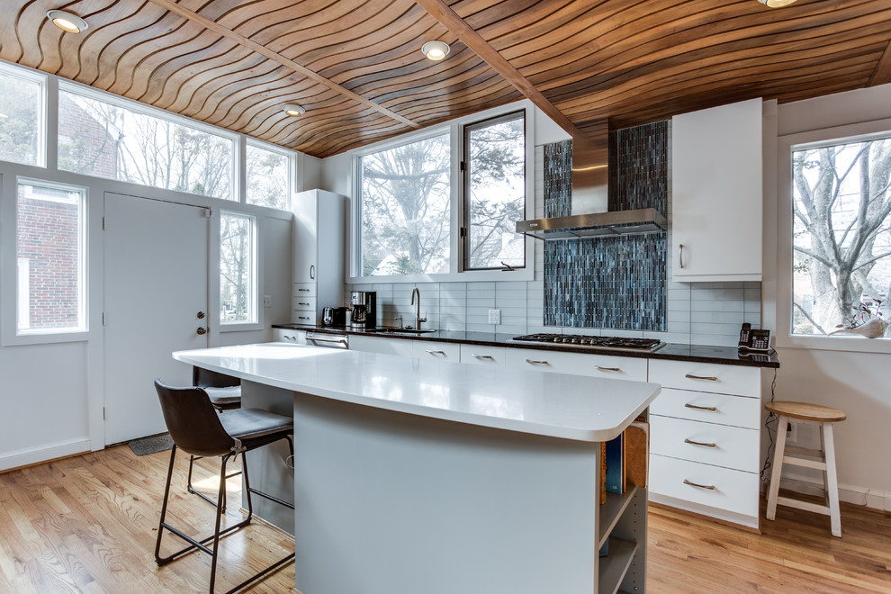 Inspiration for a mid-sized modern medium tone wood floor kitchen remodel in DC Metro with an undermount sink, flat-panel cabinets, quartz countertops, white backsplash, glass tile backsplash, stainless steel appliances and an island