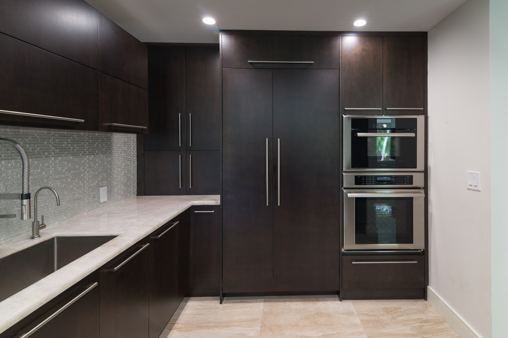 Photo of a medium sized modern l-shaped kitchen/diner in Miami with flat-panel cabinets, dark wood cabinets, metallic splashback, glass tiled splashback, stainless steel appliances and an island.