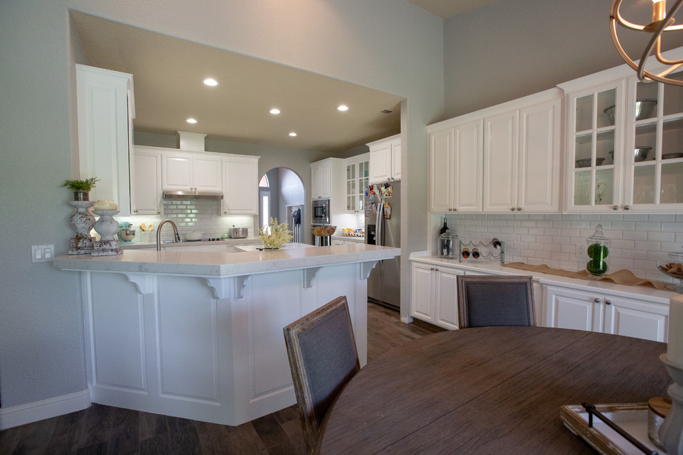 Photo of a modern u-shaped kitchen in Sacramento with a submerged sink, white cabinets, engineered stone countertops, white splashback, ceramic splashback, stainless steel appliances, an island and white worktops.