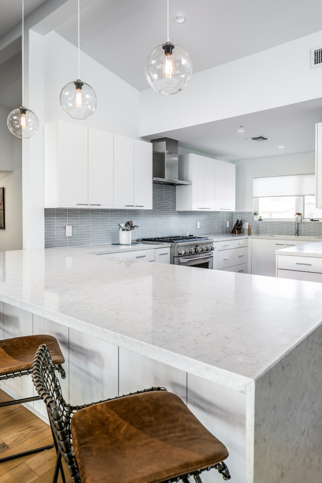 Idéer för att renovera ett funkis vit vitt kök, med släta luckor, vita skåp, marmorbänkskiva, grått stänkskydd, stänkskydd i keramik, rostfria vitvaror, mellanmörkt trägolv och brunt golv