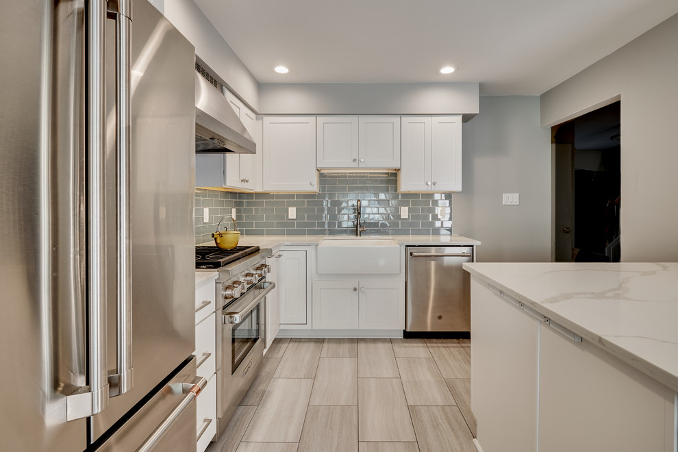 Idéer för ett avskilt, litet modernt vit l-kök, med en rustik diskho, luckor med infälld panel, vita skåp, bänkskiva i kvarts, blått stänkskydd, stänkskydd i glaskakel, rostfria vitvaror, vinylgolv, en köksö och beiget golv