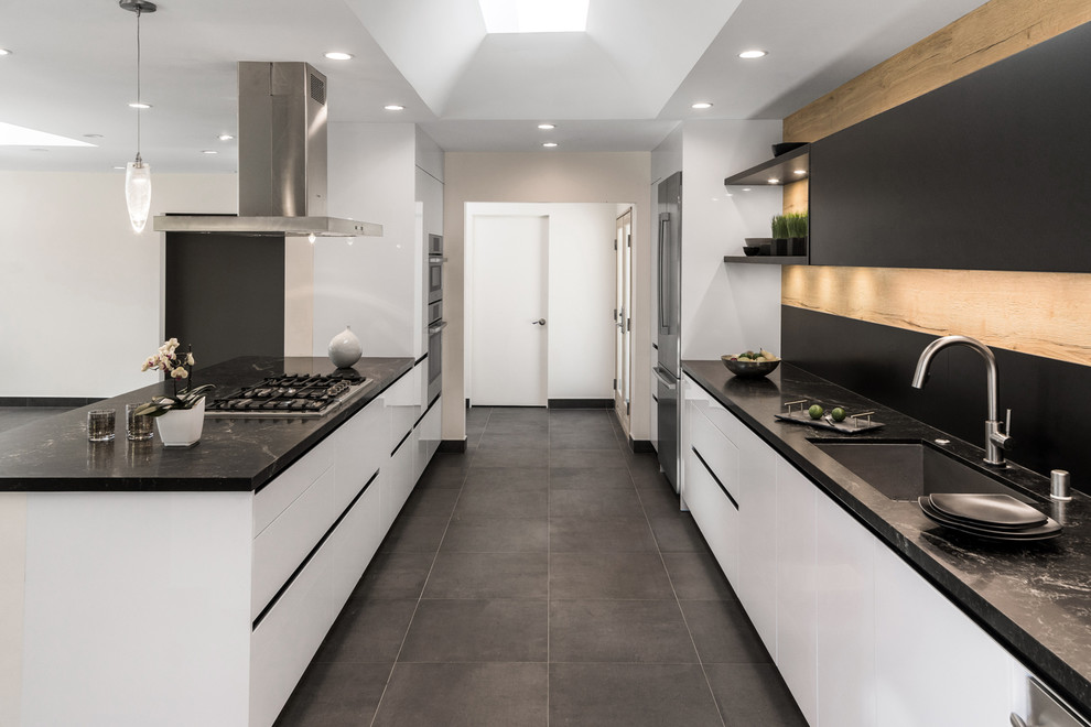 Example of a minimalist galley eat-in kitchen design in Los Angeles with white cabinets and an island