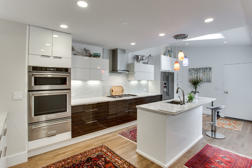 ワシントンD.C.にある中くらいなモダンスタイルのおしゃれなキッチン (アンダーカウンターシンク、フラットパネル扉のキャビネット、白いキッチンパネル、シルバーの調理設備、無垢フローリング) の写真