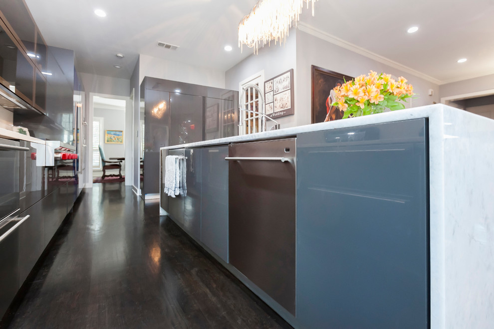 Photo of a large modern l-shaped kitchen/diner in Dallas with a built-in sink, flat-panel cabinets, stainless steel cabinets, marble worktops, white splashback, stainless steel appliances, dark hardwood flooring, an island and brown floors.