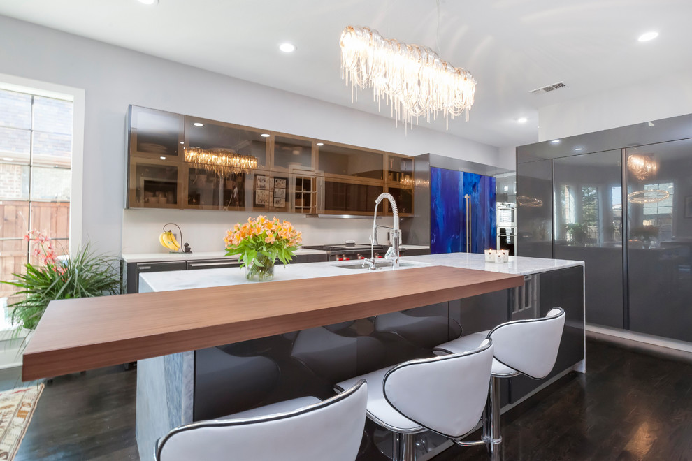 This is an example of a large modern l-shaped kitchen/diner in Dallas with a built-in sink, glass-front cabinets, stainless steel cabinets, granite worktops, white splashback, stone tiled splashback, stainless steel appliances, dark hardwood flooring, an island, brown floors and white worktops.