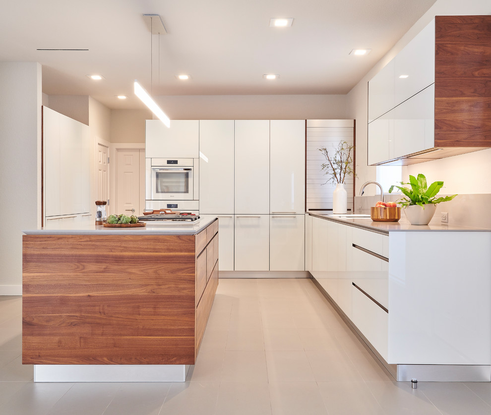 Moderne Küche in L-Form mit Porzellan-Bodenfliesen, grauem Boden, flächenbündigen Schrankfronten, hellbraunen Holzschränken, Küchenrückwand in Grau, weißen Elektrogeräten, Kücheninsel und grauer Arbeitsplatte in Dallas