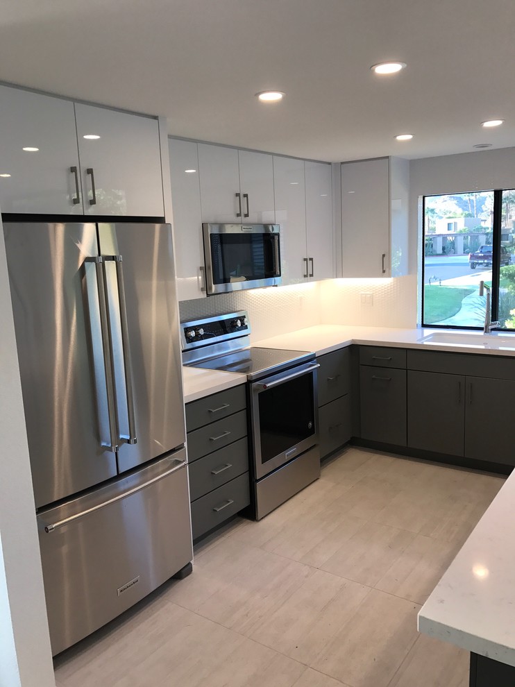 Photo of a large modern l-shaped kitchen/diner in Other with a submerged sink, flat-panel cabinets, white cabinets, quartz worktops, white splashback, stainless steel appliances, porcelain flooring, an island and grey floors.