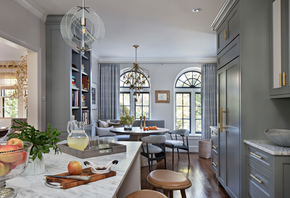 Inspiration for a large transitional u-shaped medium tone wood floor enclosed kitchen remodel in Philadelphia with flat-panel cabinets, gray cabinets, an island, a farmhouse sink, marble countertops, marble backsplash and paneled appliances