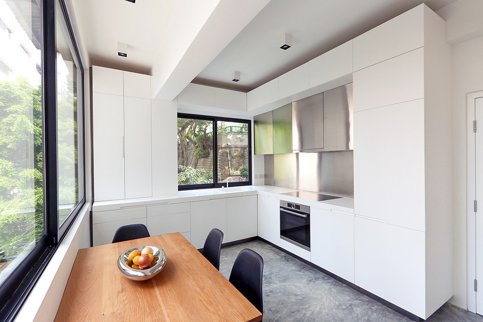 Inspiration för ett funkis kök, med släta luckor, vita skåp, stänkskydd med metallisk yta, rostfria vitvaror och betonggolv