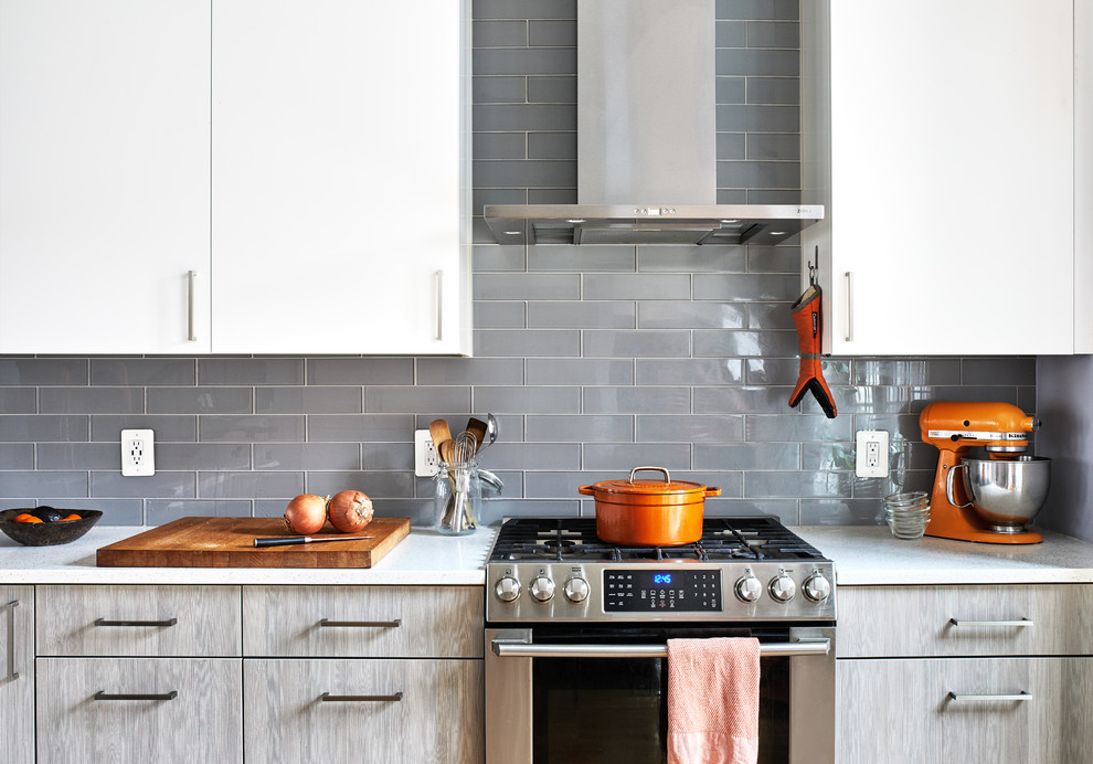 ワシントンD.C.にあるお手頃価格の広いコンテンポラリースタイルのおしゃれなキッチン (アンダーカウンターシンク、フラットパネル扉のキャビネット、白いキャビネット、珪岩カウンター、青いキッチンパネル、ガラスタイルのキッチンパネル、シルバーの調理設備、淡色無垢フローリング、白いキッチンカウンター) の写真