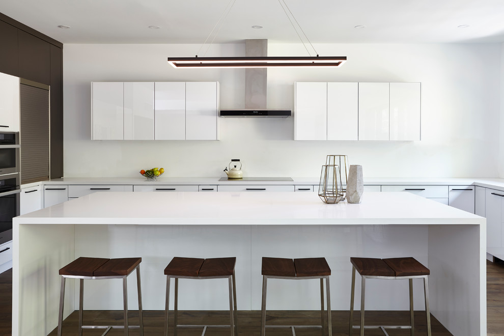 Idée de décoration pour une cuisine minimaliste en U avec un placard à porte plane, des portes de placard blanches, îlot et un plan de travail blanc.