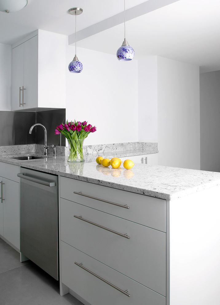 Medium sized modern l-shaped open plan kitchen in New York with a submerged sink, white cabinets, stainless steel appliances, an island, shaker cabinets, engineered stone countertops, white splashback, matchstick tiled splashback and slate flooring.