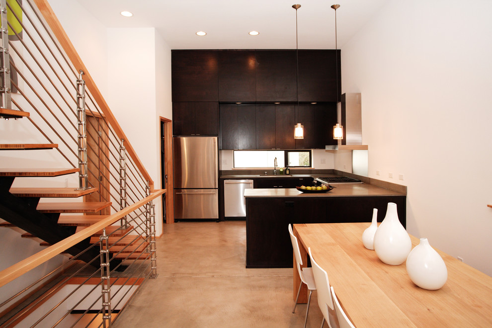 Modern u-shaped kitchen/diner in Seattle with stainless steel appliances, flat-panel cabinets and dark wood cabinets.