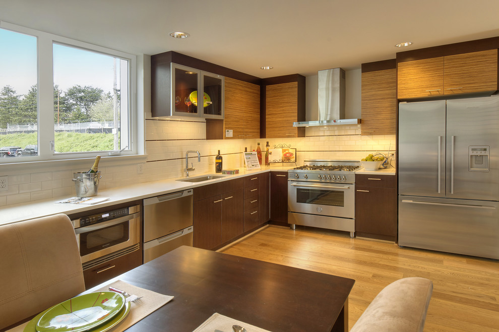 Moderne Wohnküche in L-Form mit Küchengeräten aus Edelstahl, Waschbecken, flächenbündigen Schrankfronten, hellbraunen Holzschränken, Küchenrückwand in Weiß und Rückwand aus Metrofliesen in Seattle