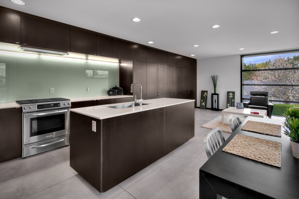 Photo of a modern open plan kitchen in Seattle with stainless steel appliances, a single-bowl sink, flat-panel cabinets, dark wood cabinets and glass sheet splashback.