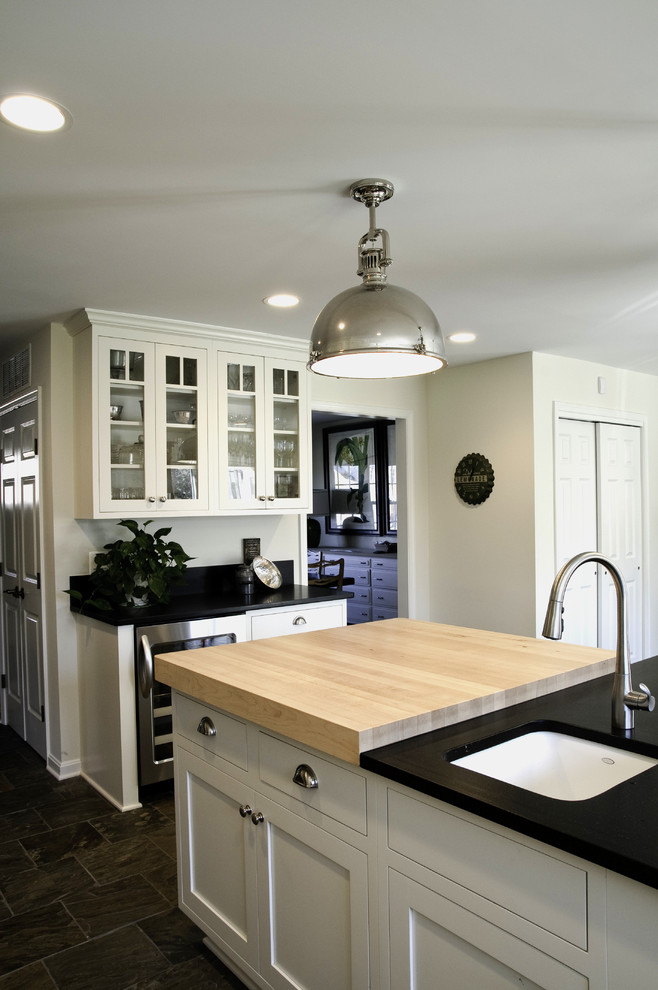 Immagine di una cucina minimalista con lavello sottopiano, ante con riquadro incassato, ante bianche, top in granito, paraspruzzi grigio e elettrodomestici in acciaio inossidabile