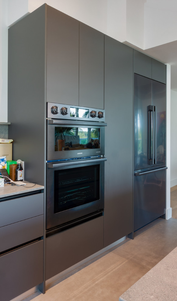 Photo of a medium sized modern l-shaped enclosed kitchen in Miami with flat-panel cabinets, grey cabinets, concrete worktops, grey splashback, cement tile splashback, stainless steel appliances, an island and grey worktops.