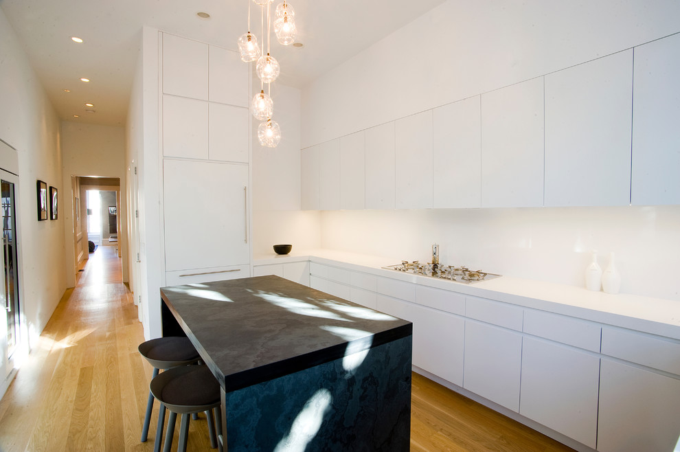 Modern kitchen in San Francisco with flat-panel cabinets, white cabinets, white splashback, glass sheet splashback and integrated appliances.