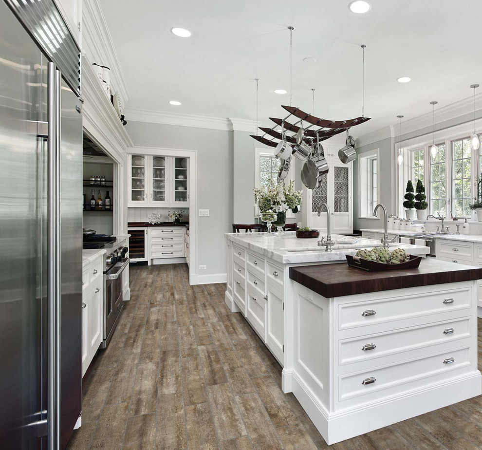 Inspiration for a mid-sized modern u-shaped medium tone wood floor enclosed kitchen remodel in Atlanta with a farmhouse sink, white cabinets, marble countertops, stainless steel appliances and an island