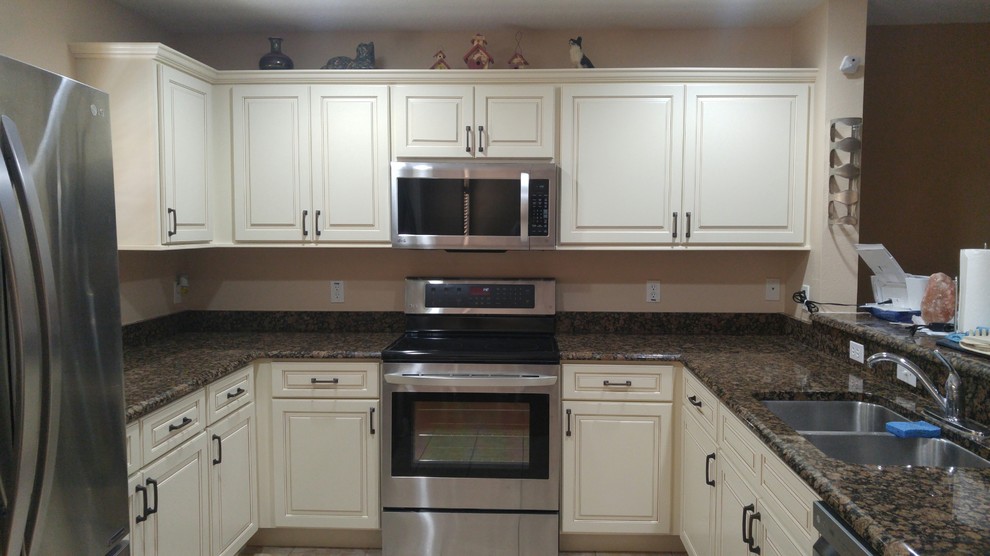 Immagine di una piccola cucina moderna con lavello sottopiano, ante con bugna sagomata, ante bianche, top in granito e elettrodomestici in acciaio inossidabile