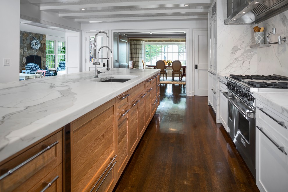 Large minimalist single-wall dark wood floor and brown floor open concept kitchen photo in New York with an undermount sink, shaker cabinets, white cabinets, marble countertops, white backsplash, stone slab backsplash, stainless steel appliances and an island