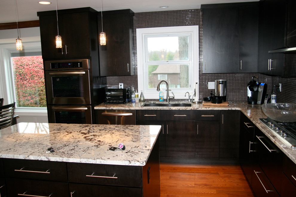 Bild på ett funkis kök, med en undermonterad diskho, skåp i shakerstil, skåp i mörkt trä, granitbänkskiva, stänkskydd i glaskakel och rostfria vitvaror