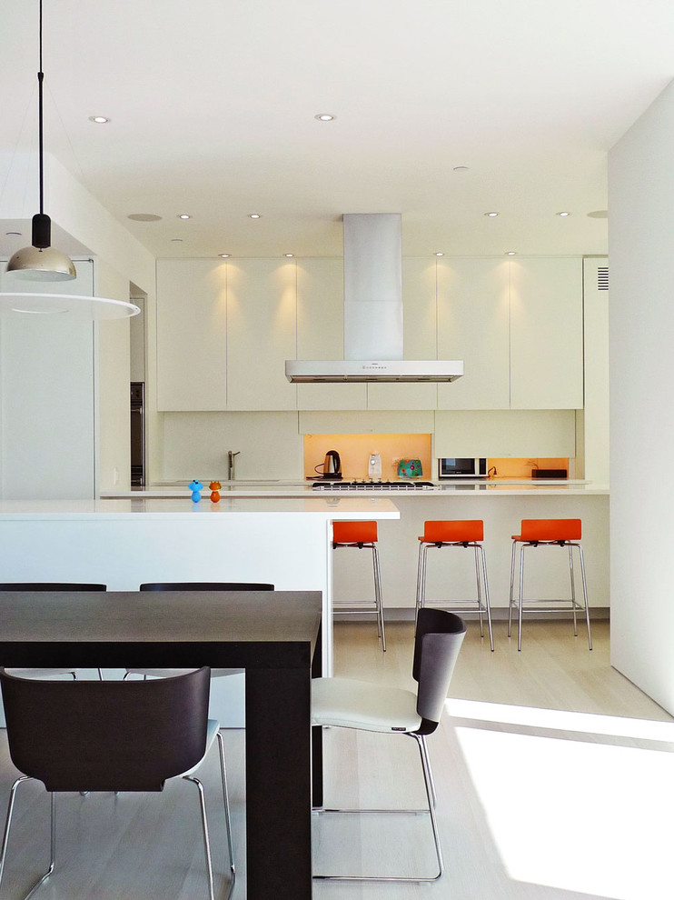 Пример оригинального дизайна: кухня в стиле модернизм с обеденным столом, плоскими фасадами, белыми фасадами и оранжевым фартуком