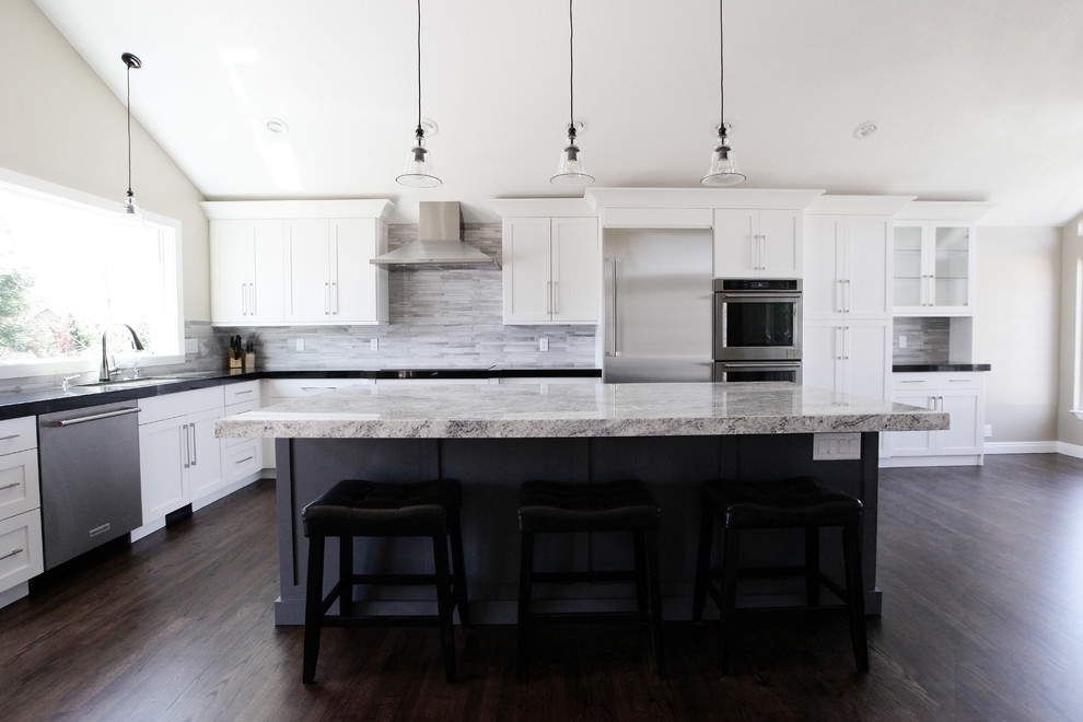 Bild på ett mellanstort funkis kök och matrum, med en undermonterad diskho, släta luckor, vita skåp, granitbänkskiva, stänkskydd i keramik, rostfria vitvaror, mörkt trägolv och en köksö
