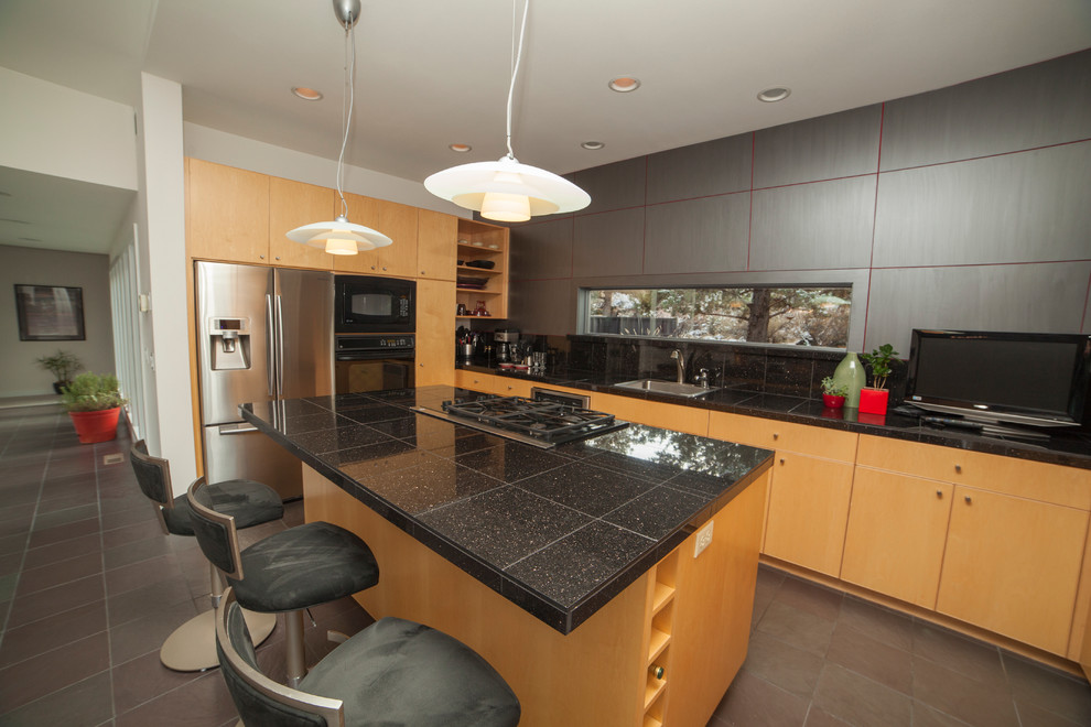 Example of a minimalist kitchen design in Portland with stainless steel appliances and black countertops