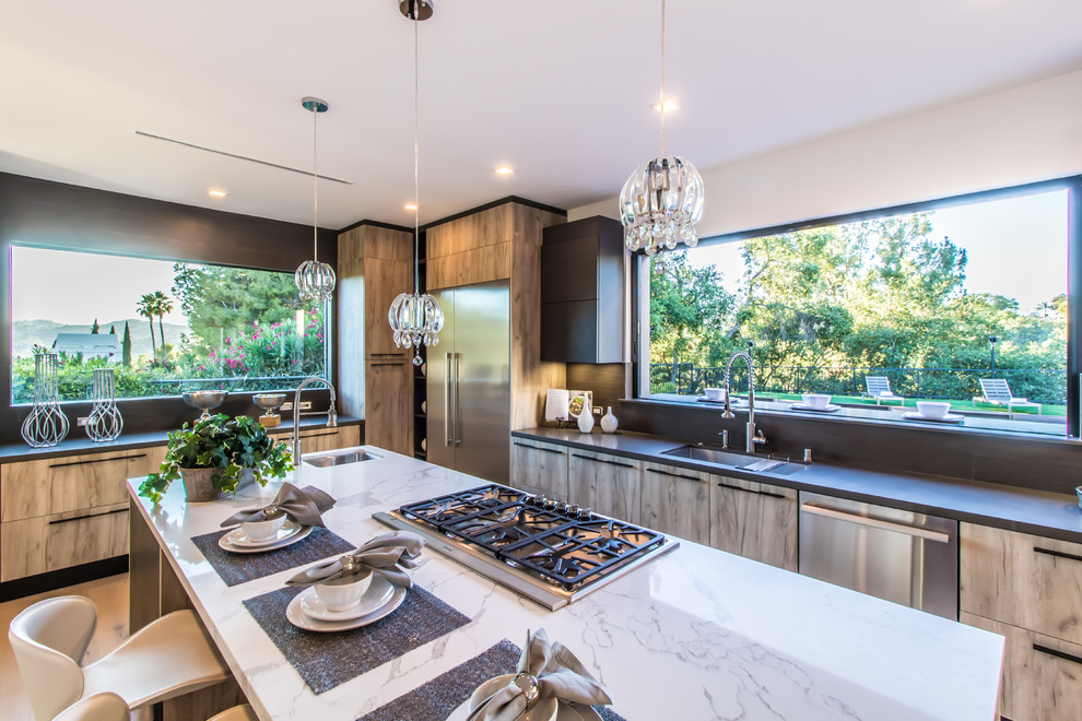 Inspiration for a large modern l-shaped light wood floor and beige floor eat-in kitchen remodel in Los Angeles with a drop-in sink, flat-panel cabinets, brown cabinets, marble countertops, stainless steel appliances, an island and white countertops