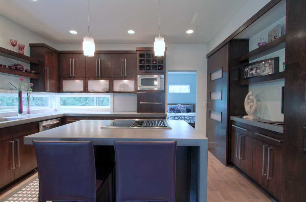 This is an example of a medium sized modern l-shaped kitchen/diner in Portland with a submerged sink, flat-panel cabinets, dark wood cabinets, concrete worktops, stainless steel appliances, medium hardwood flooring and an island.