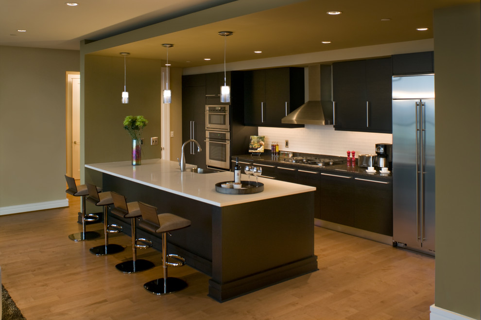 Exempel på ett stort modernt kök, med en undermonterad diskho, släta luckor, skåp i mörkt trä, bänkskiva i kvarts, vitt stänkskydd, stänkskydd i keramik, rostfria vitvaror, ljust trägolv, en köksö och beiget golv
