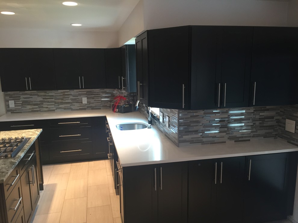 Mittelgroße Moderne Küche in L-Form mit Unterbauwaschbecken, schwarzen Schränken, Quarzit-Arbeitsplatte, bunter Rückwand, Rückwand aus Glasfliesen, Keramikboden und Kücheninsel in Cleveland