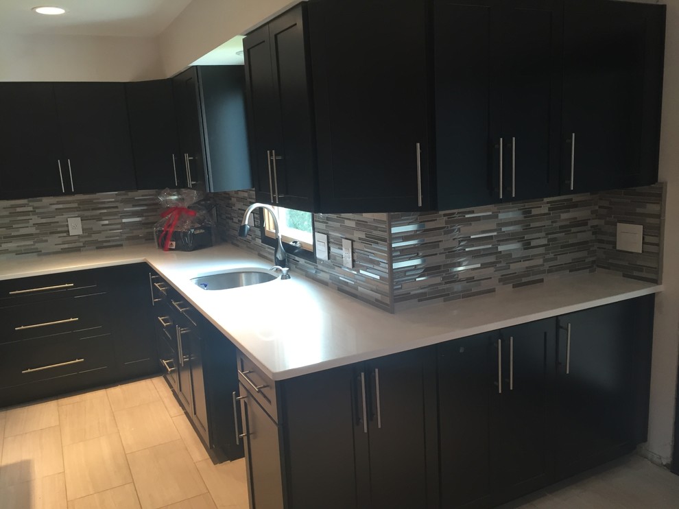 Mittelgroße Moderne Küche in L-Form mit Unterbauwaschbecken, schwarzen Schränken, Quarzit-Arbeitsplatte, bunter Rückwand, Rückwand aus Glasfliesen, Keramikboden und Kücheninsel in Cleveland
