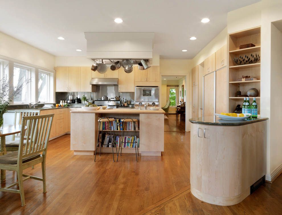 Foto på ett mellanstort funkis kök, med en undermonterad diskho, släta luckor, skåp i ljust trä, granitbänkskiva, stänkskydd med metallisk yta, integrerade vitvaror, mellanmörkt trägolv, en köksö och stänkskydd i metallkakel
