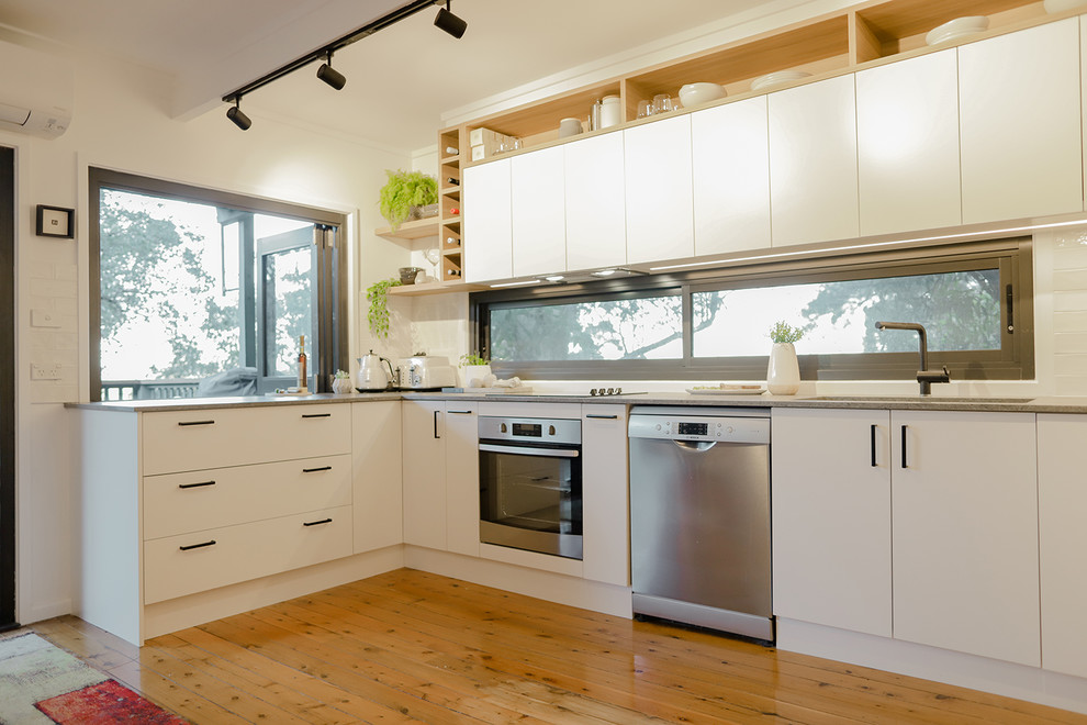 Idéer för ett mellanstort modernt grå kök, med en undermonterad diskho, släta luckor, vita skåp, bänkskiva i kvarts, grått stänkskydd, fönster som stänkskydd, rostfria vitvaror, ljust trägolv och orange golv