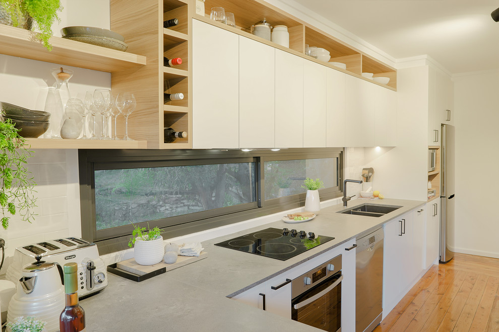Inspiration för mellanstora moderna grått kök, med en undermonterad diskho, släta luckor, vita skåp, bänkskiva i kvarts, grått stänkskydd, fönster som stänkskydd, rostfria vitvaror, ljust trägolv och orange golv