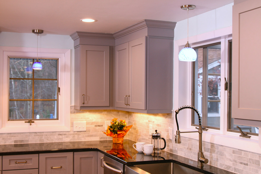 Example of a mid-sized trendy l-shaped medium tone wood floor eat-in kitchen design in Boston with a farmhouse sink, recessed-panel cabinets, gray cabinets, solid surface countertops, gray backsplash, porcelain backsplash, stainless steel appliances and an island