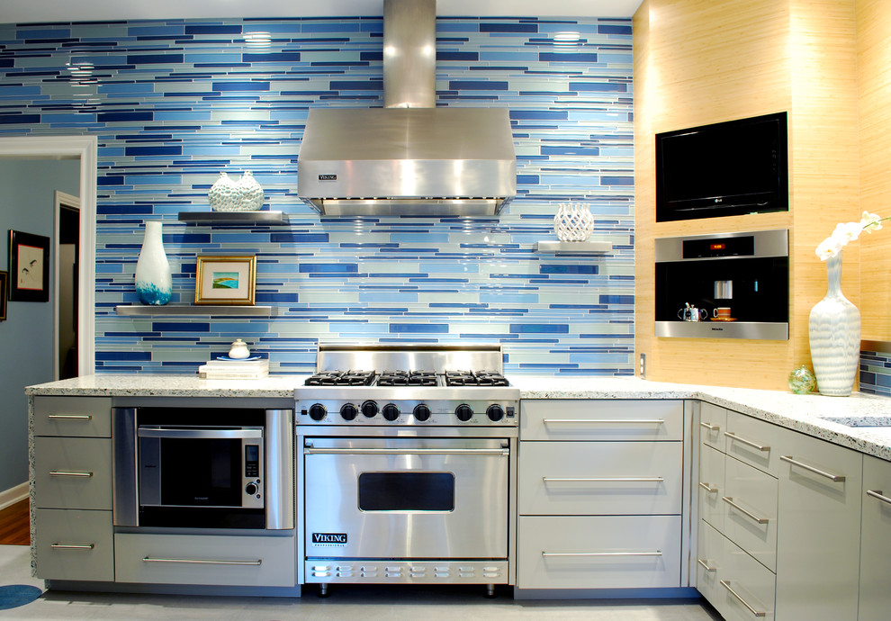 Ejemplo de cocina contemporánea con encimera de vidrio reciclado, armarios con paneles lisos, puertas de armario grises, salpicadero azul, salpicadero de azulejos de vidrio y electrodomésticos de acero inoxidable