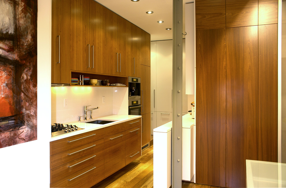 Small modern single-wall kitchen in New York with flat-panel cabinets, medium wood cabinets, a single-bowl sink, quartz worktops, stainless steel appliances, medium hardwood flooring and a breakfast bar.