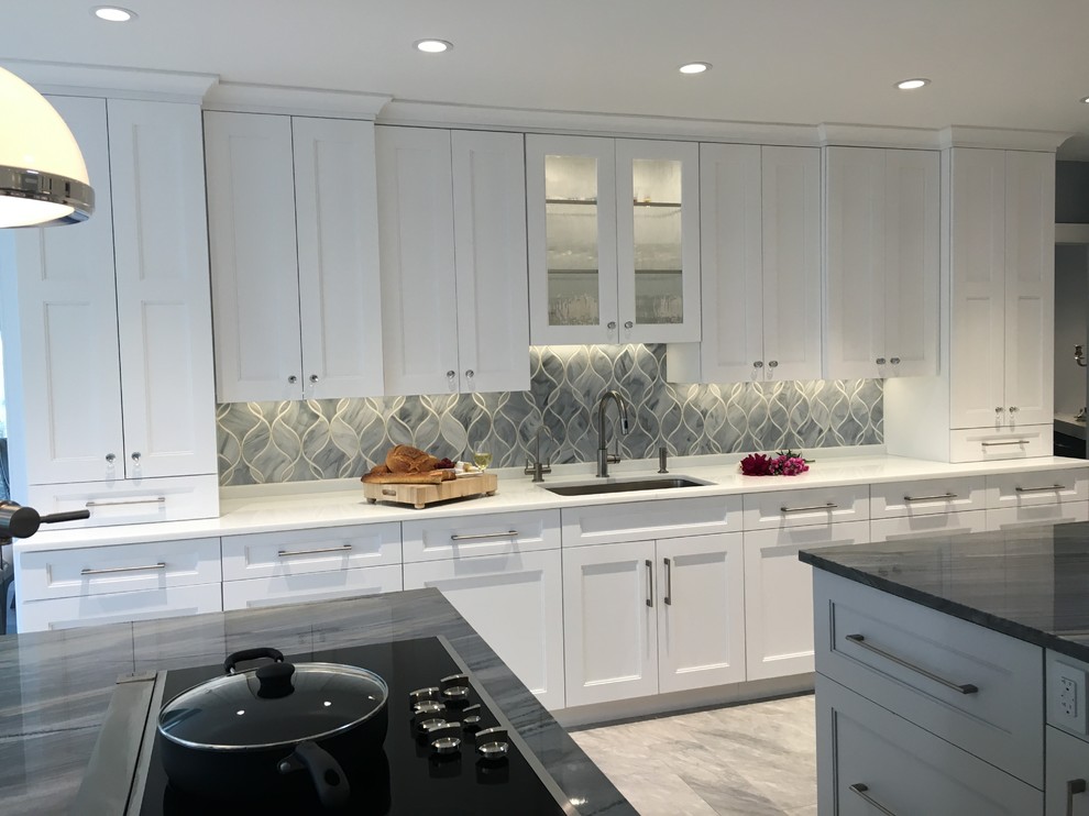 Inspiration for a huge contemporary u-shaped ceramic tile eat-in kitchen remodel in New York with a single-bowl sink, shaker cabinets, white cabinets, quartzite countertops, gray backsplash, glass sheet backsplash, stainless steel appliances and two islands