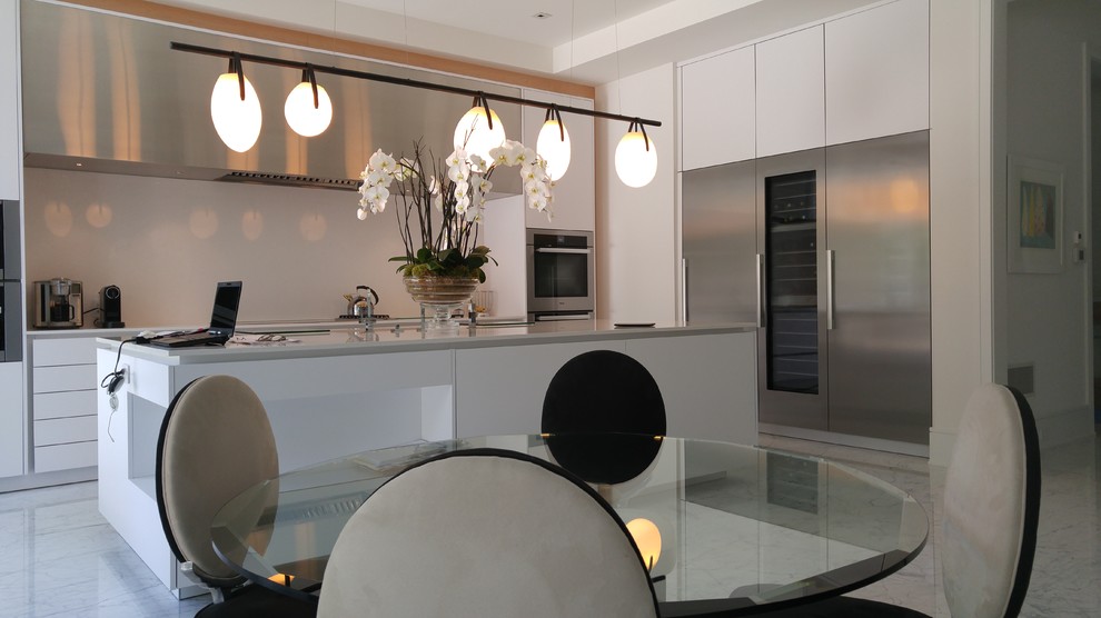 Immagine di un grande cucina con isola centrale minimalista con ante bianche, elettrodomestici in acciaio inossidabile e pavimento in marmo