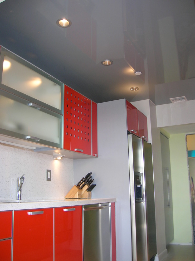 Moderne Wohnküche in U-Form mit Einbauwaschbecken, Lamellenschränken, roten Schränken, Mineralwerkstoff-Arbeitsplatte, Küchenrückwand in Weiß, Rückwand aus Stein und Küchengeräten aus Edelstahl in Miami