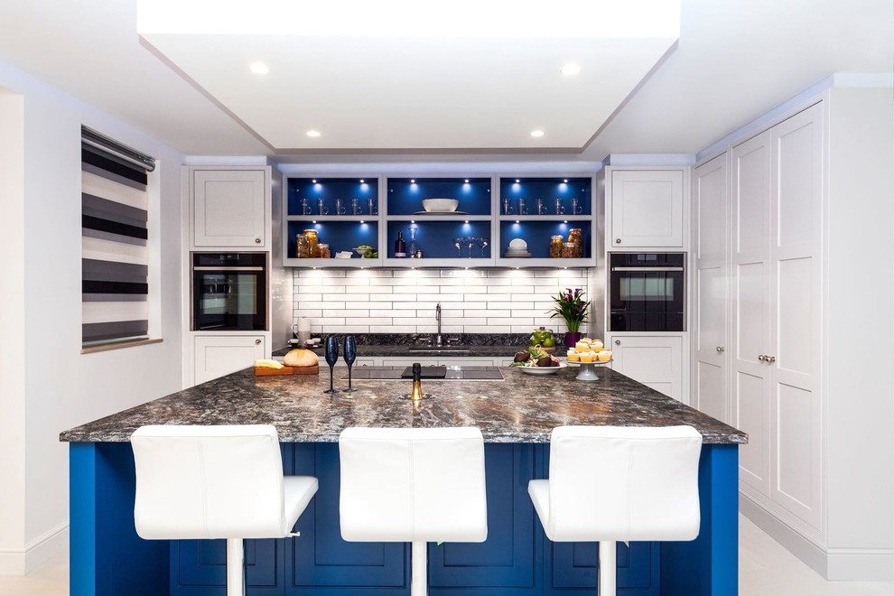 Immagine di un cucina con isola centrale chic con lavello sottopiano, ante in stile shaker, ante bianche, paraspruzzi bianco, elettrodomestici neri, pavimento bianco e top multicolore