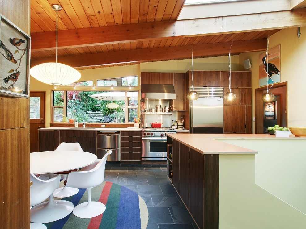 Свежая идея для дизайна: кухня среднего размера в стиле модернизм с техникой из нержавеющей стали, обеденным столом, врезной мойкой, плоскими фасадами, темными деревянными фасадами, полом из сланца и черным полом - отличное фото интерьера